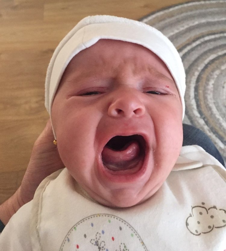 Newborn baby crying during photoshoot.