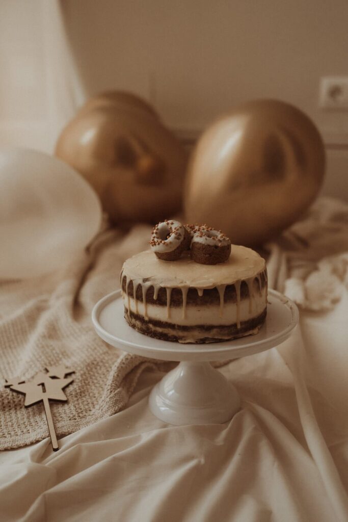 Elegant first birthday cake with golden balloons.