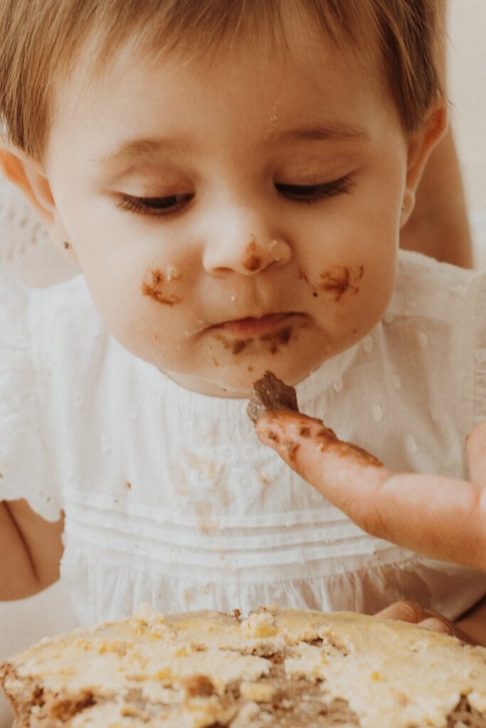 Toddler enjoying first birthday cake tasting.