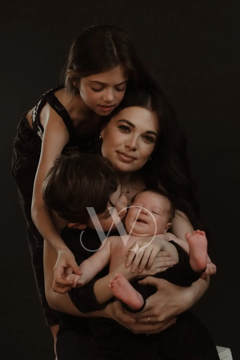 Mother and children in tender family photoshoot with newborn.