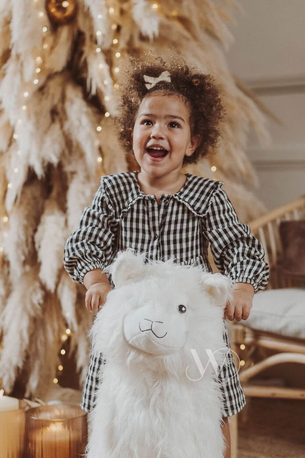 Joyful child with toy by Christmas tree.