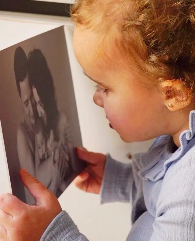 Toddler looking at black and white family photo.