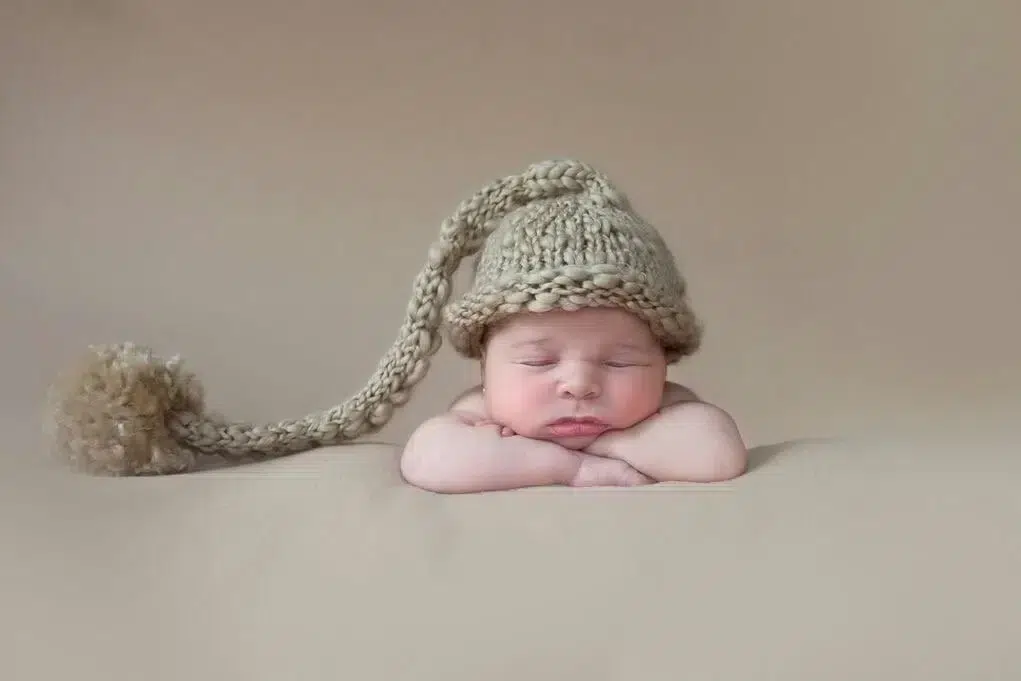 Newborn baby in cute hat posing for photo shoot.