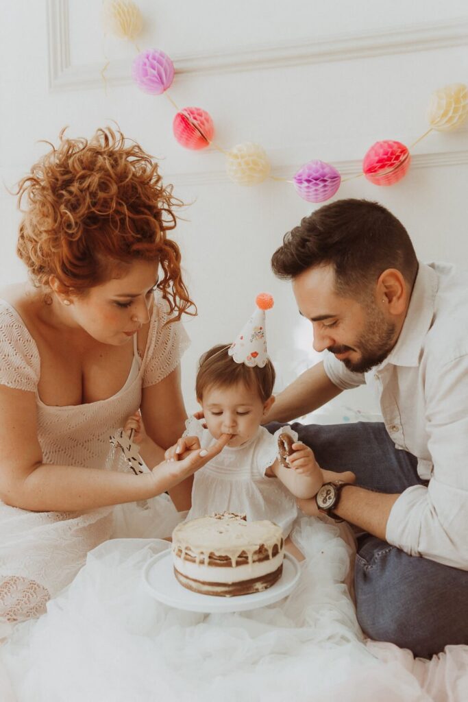 Parents and baby enjoying first birthday cake together.