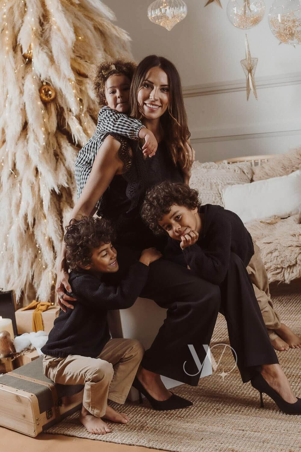 Una madre con sus dos hijos posando para una foto delante de un árbol de Navidad.