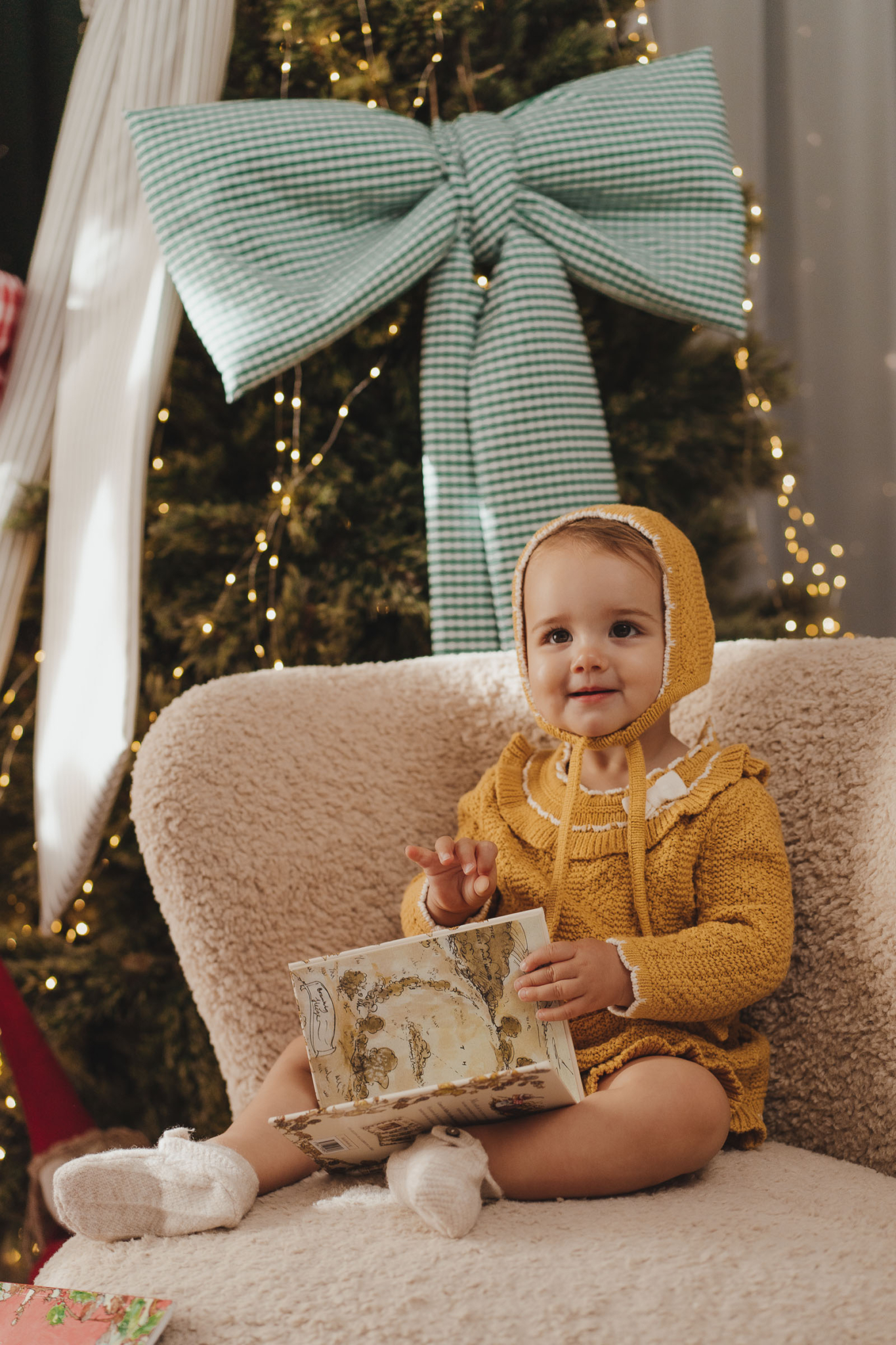 christmas photos at home baby reading by tree