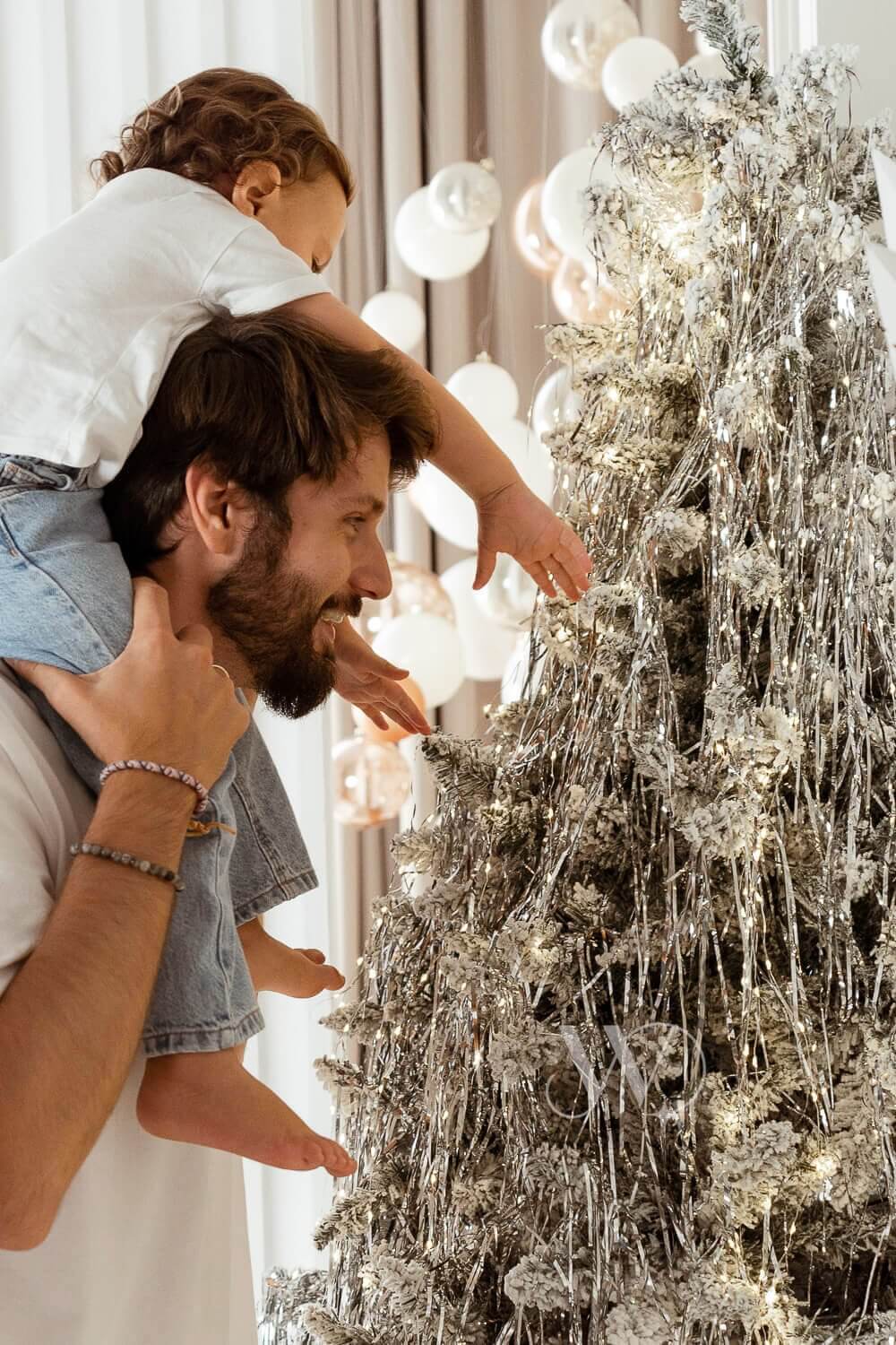 Padre e hijo de pie junto al árbol de Navidad, abrazándose.