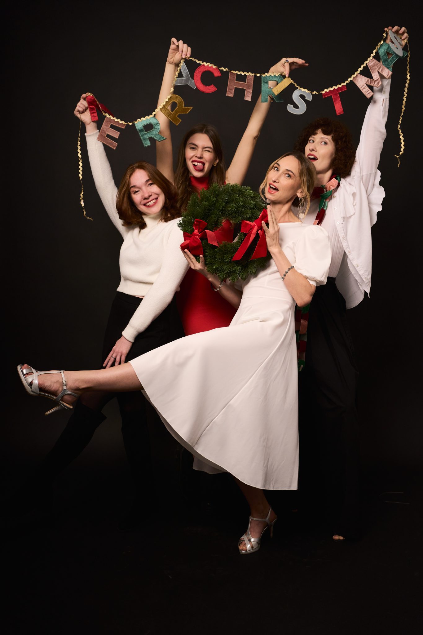 Group of friends celebrating Christmas with Merry Christmas banner and Christmas wreath - example of creative Christmas card photos