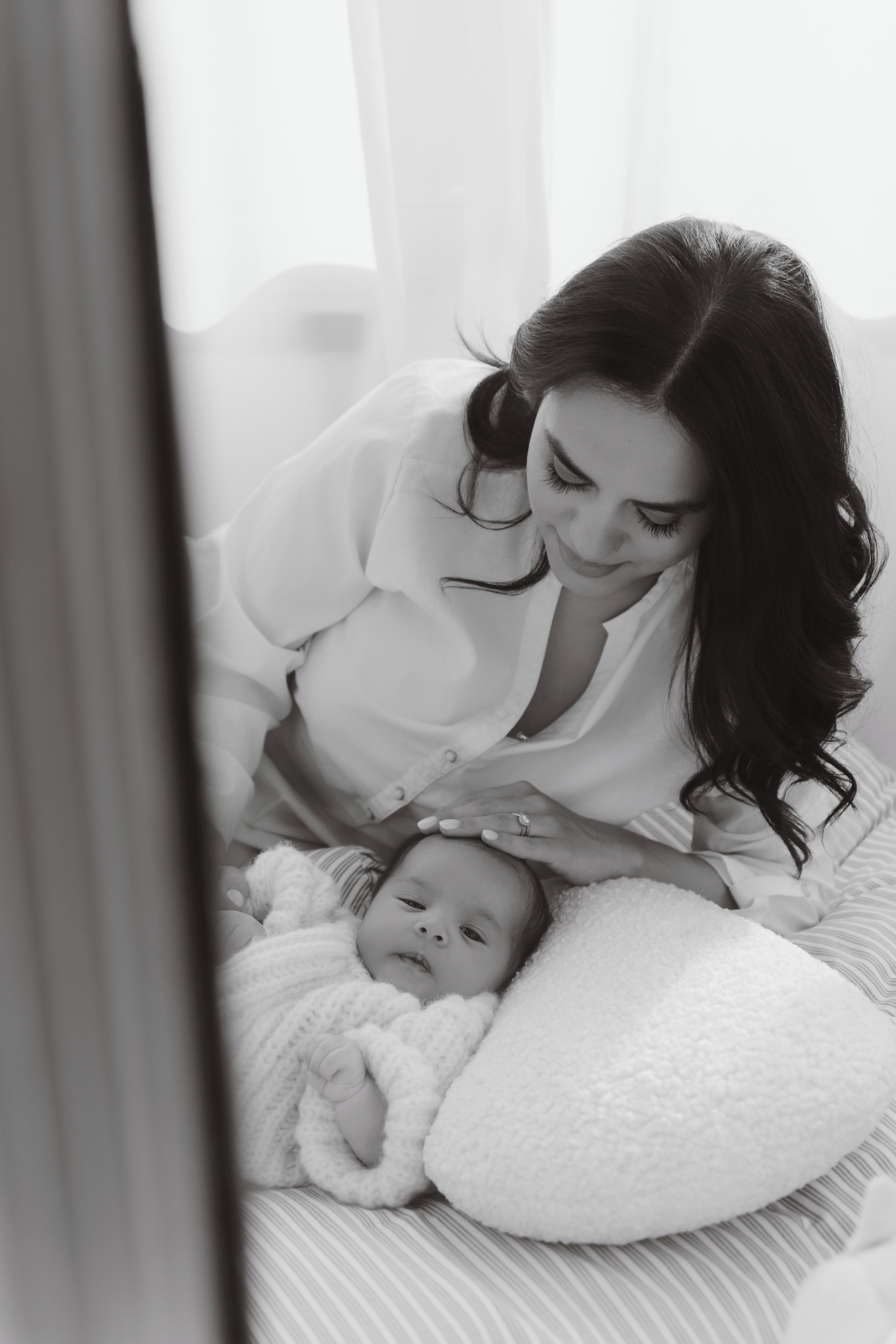 mom caressing wrapped baby newborn photos at home
