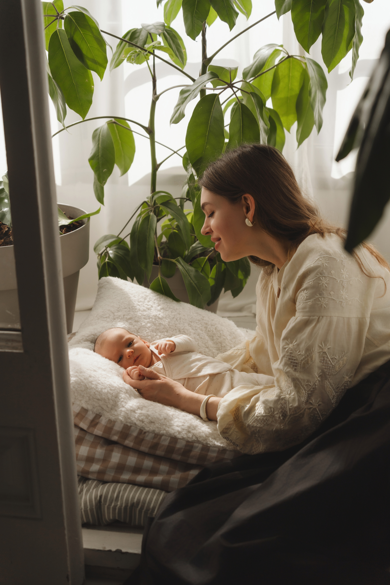 mom looking at baby window newborn photos at home