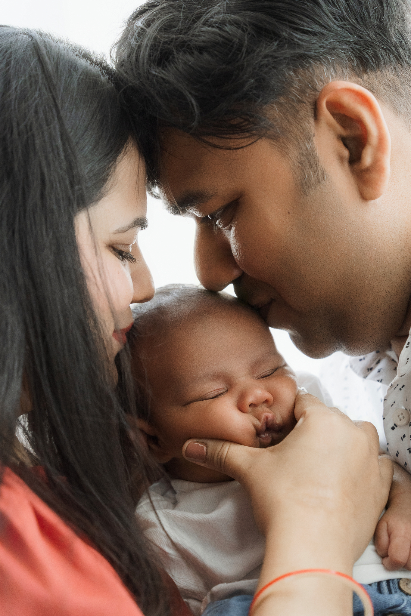 parents kissing newborn family photos intimacy