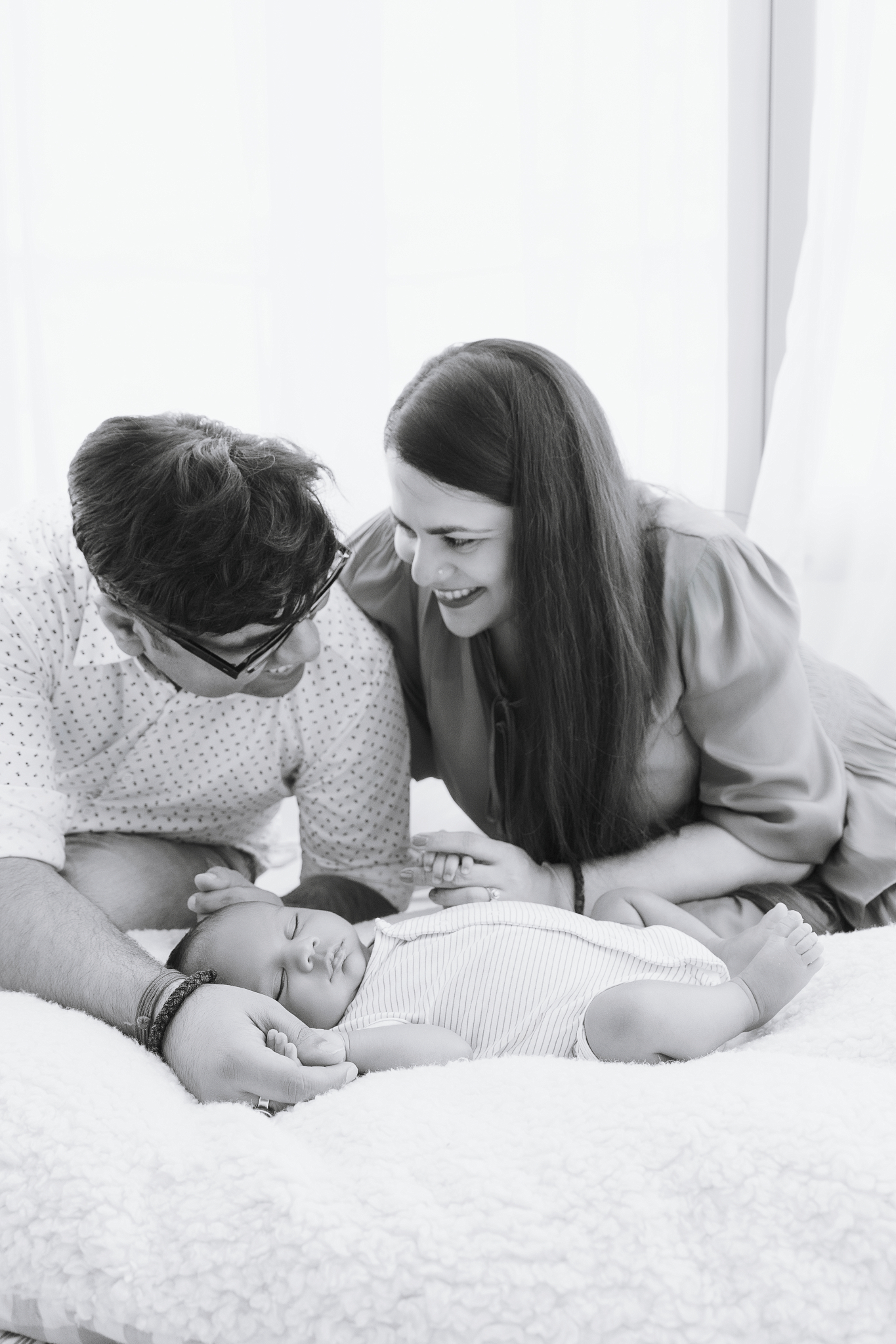 parents looking baby newborn photos home white bed