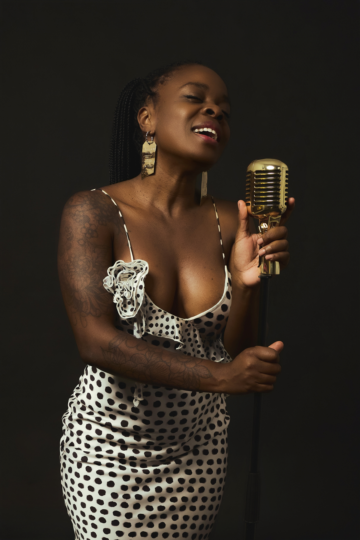 Brigitte Emaga cantando con micrófono vintage durante sesión de fotos en YOULO