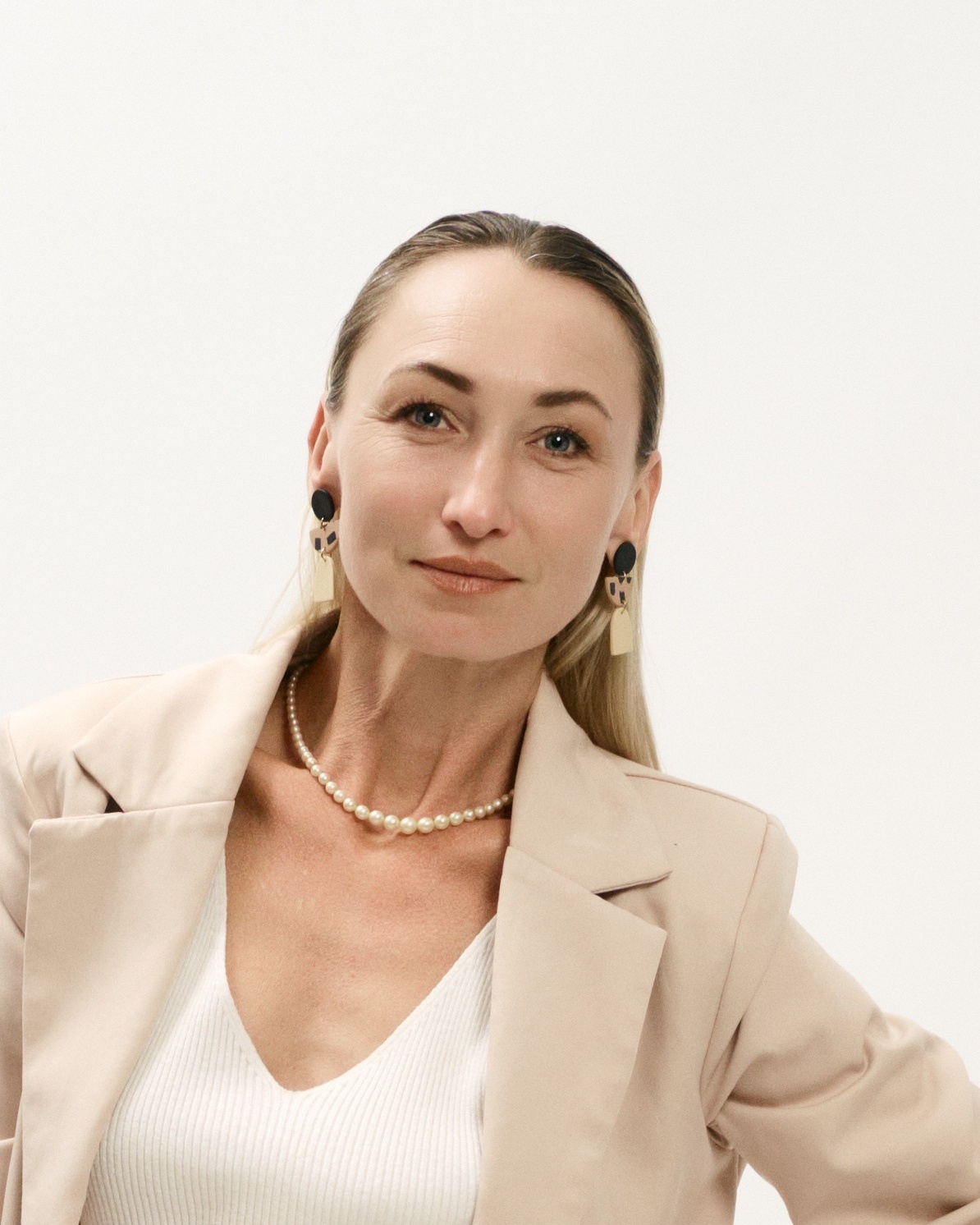 Retrato profesional de mujer directiva con blazer beige y collar de perlas en Barcelona