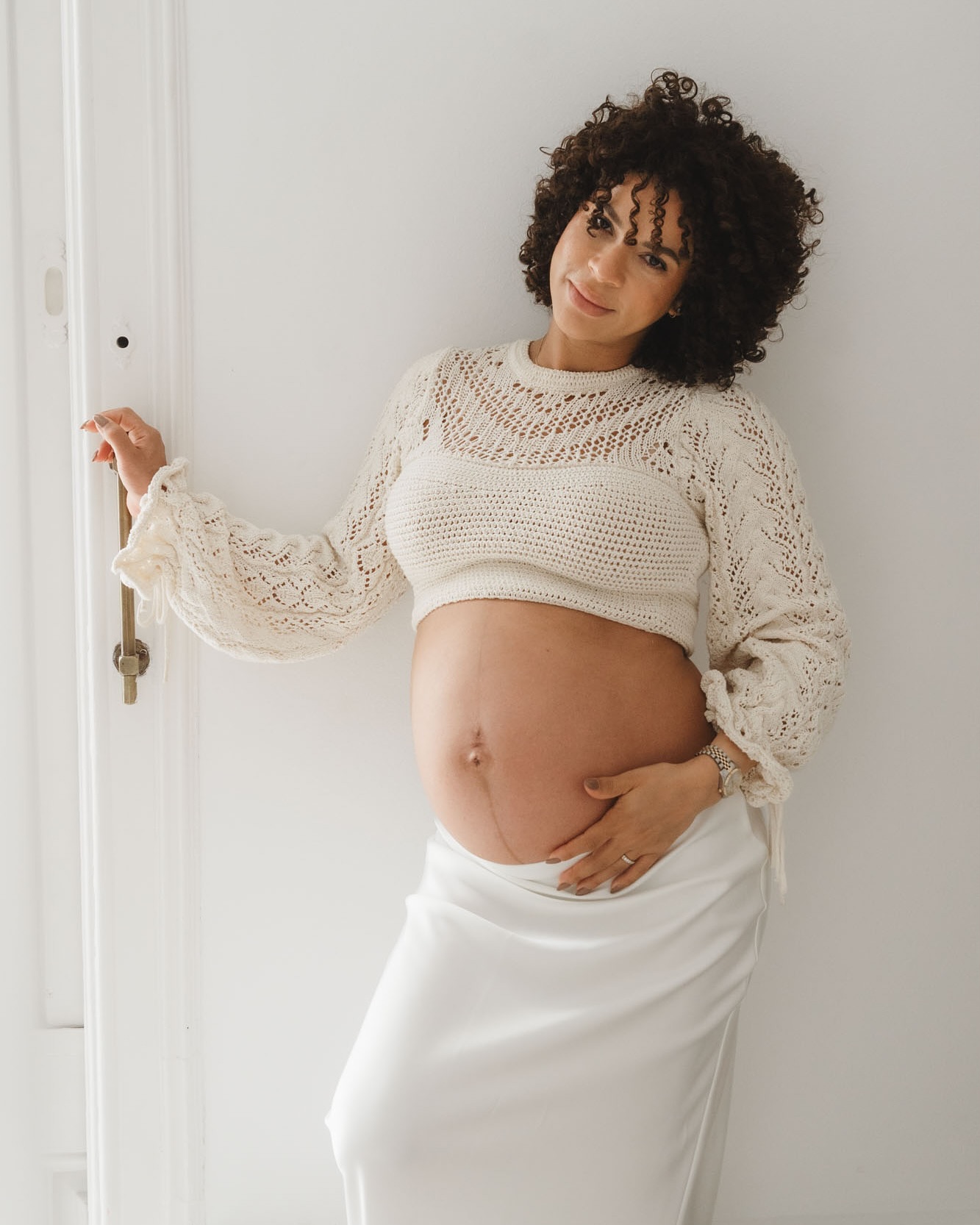 Embarazada con pelo rizado en lencería blanca, fotos embarazo cuerpo inseguridades con ropa favorecedora