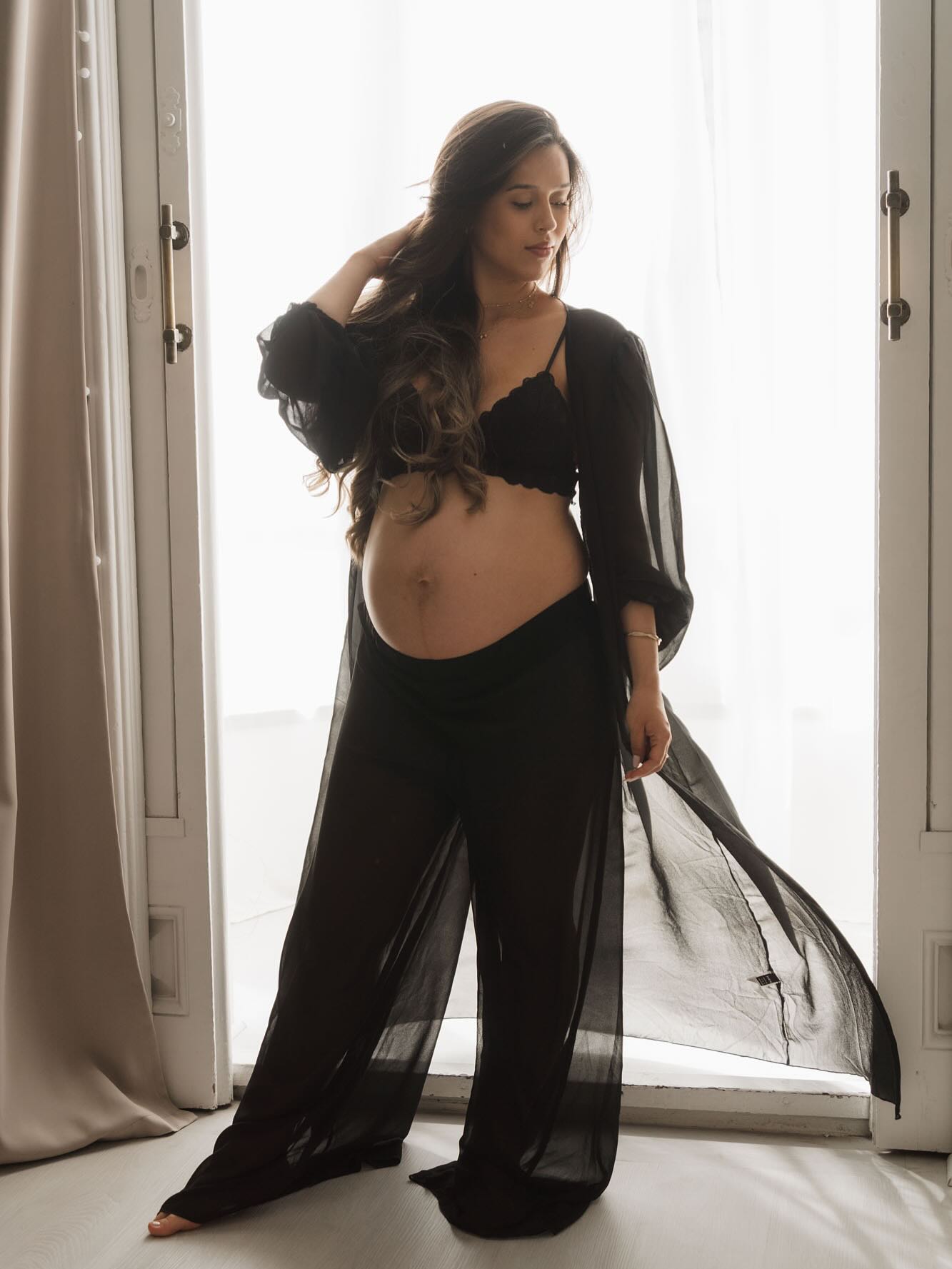 Embarazada en vestido transparente negro a contraluz en balcón, fotos embarazo cuerpo silueta íntima