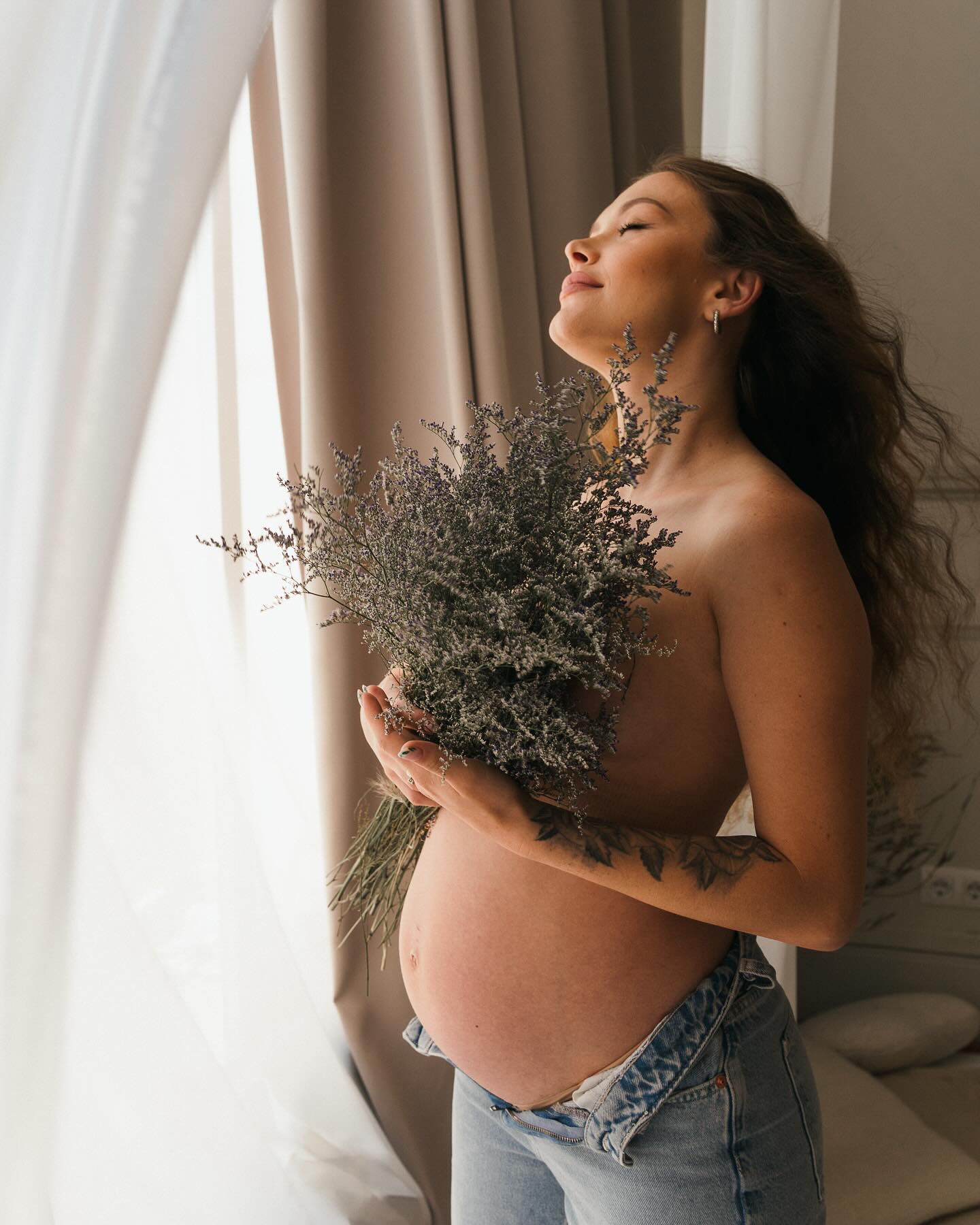 Fotos premamá en casa junto a ventana con ramo de lavanda luz natural
