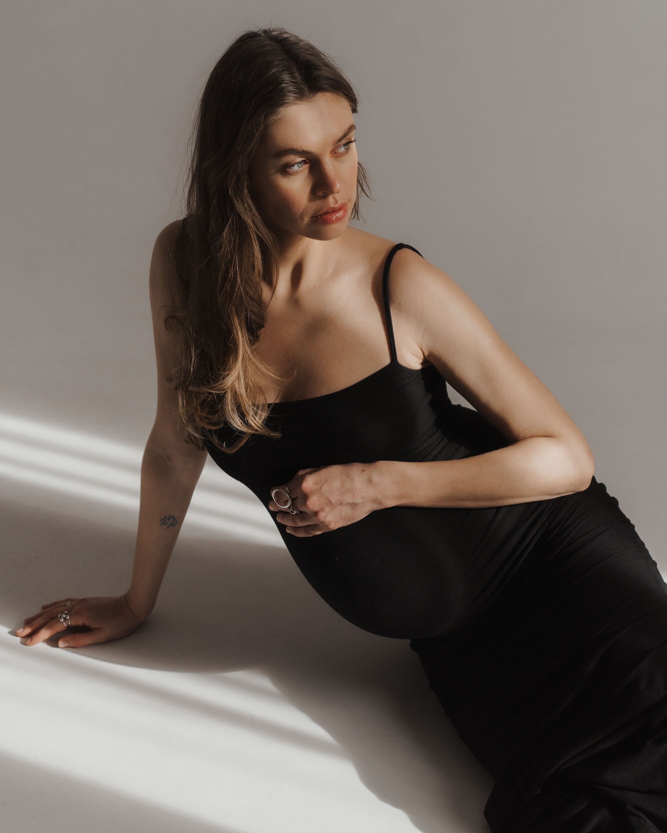 Fotos premamá en estudio con vestido negro y luz artística barriga embarazada