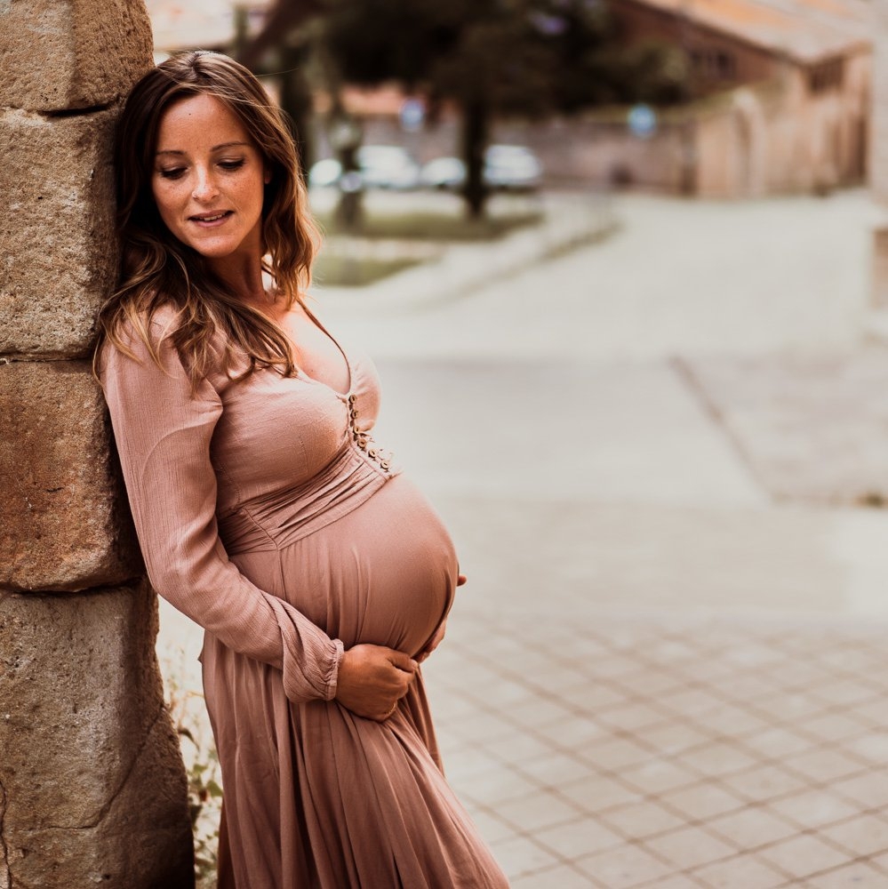Fotos premamá en exterior con pared de piedra vestido rosa embarazada