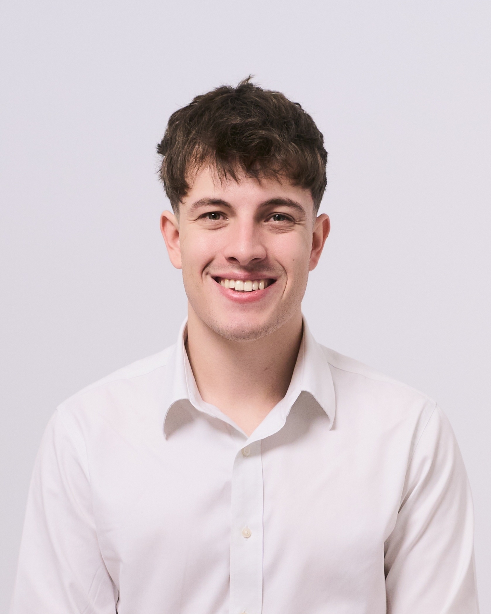 Hombre con camisa blanca sonriendo en foto profesional de estudio
