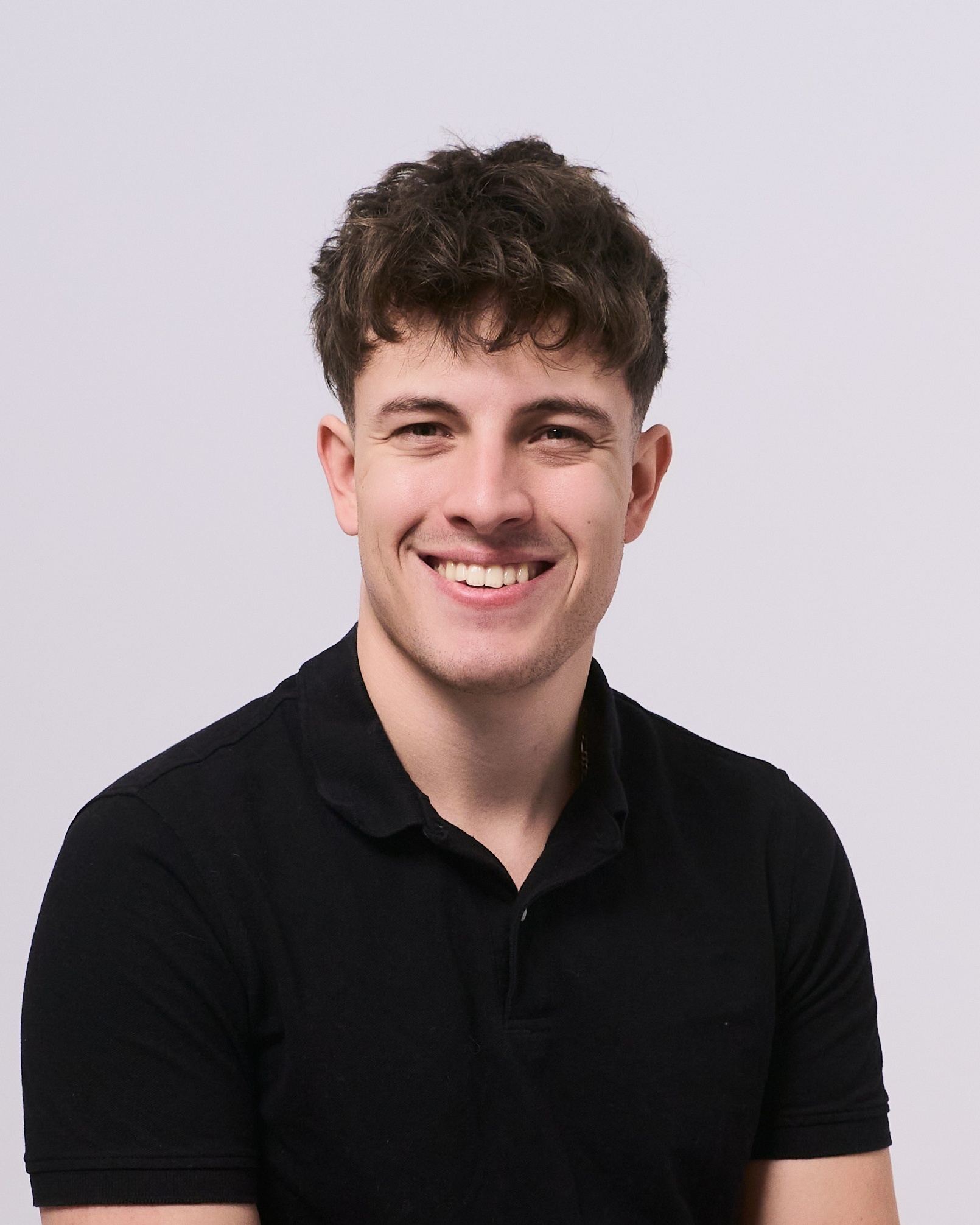 Young smiling man in black polo, professional LinkedIn photo