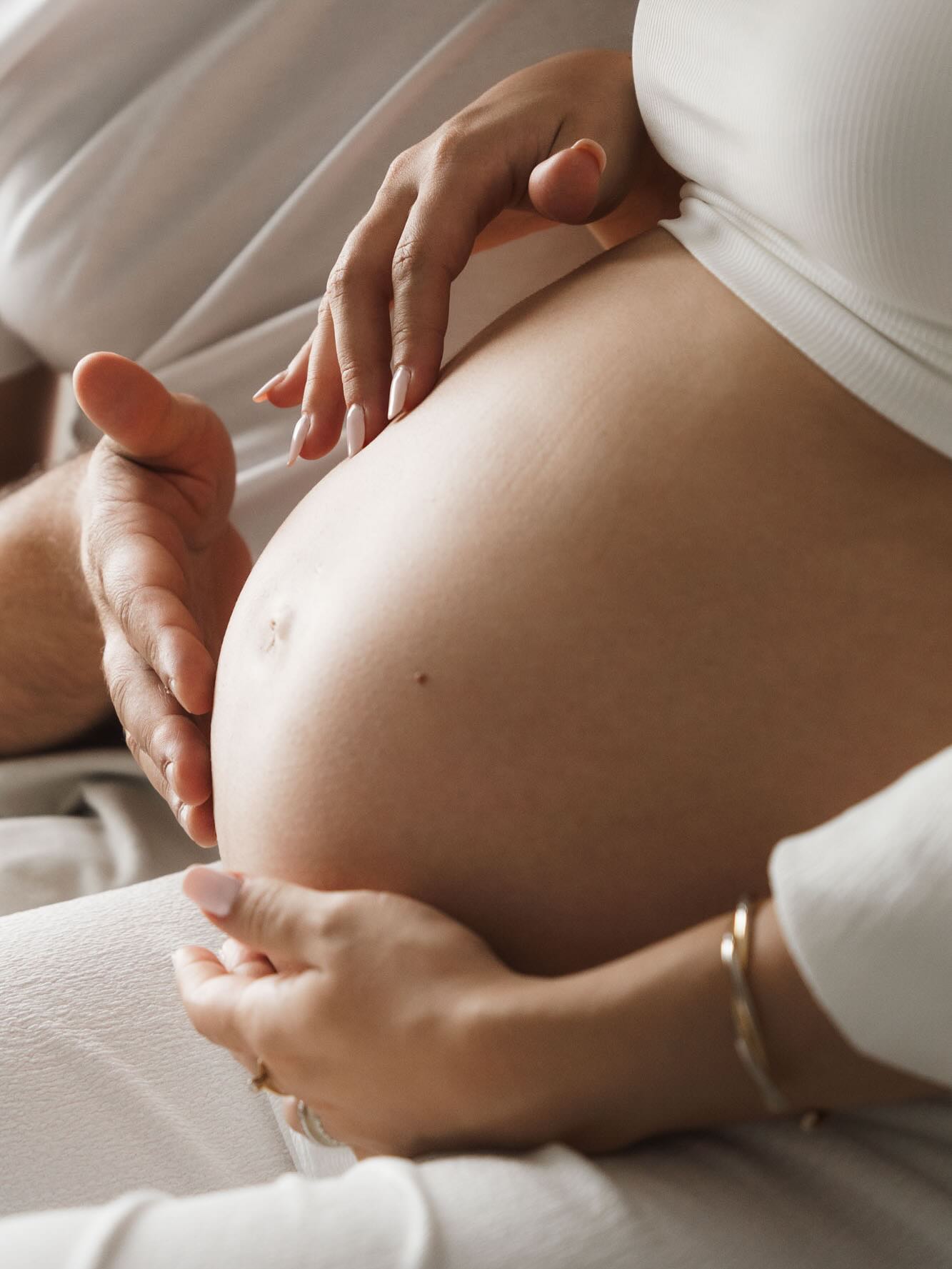 manos sobre barriga fotos embarazada en casa pareja detalle close up