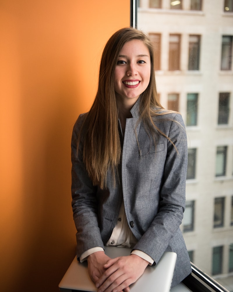 Profesional joven con blazer gris sonriendo en entorno de oficina