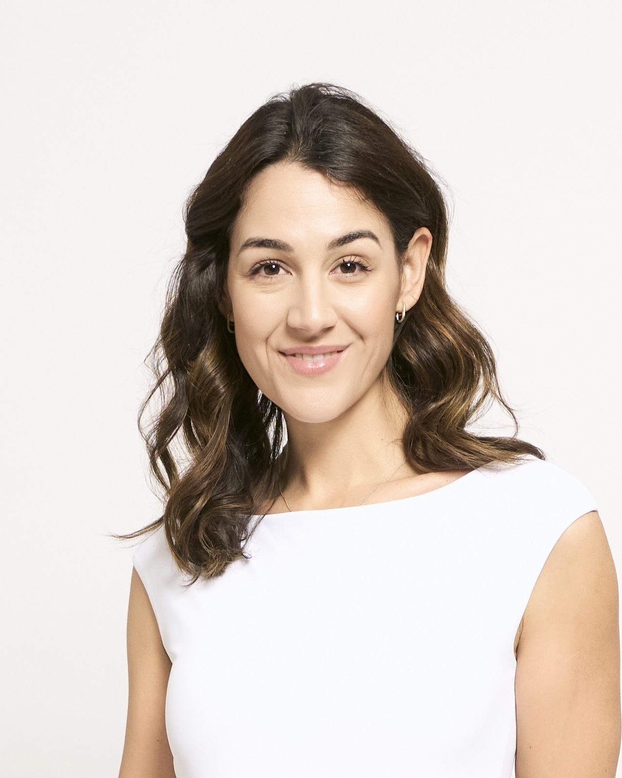 Mujer con blusa blanca sonriendo sobre fondo blanco para foto profesional de LinkedIn