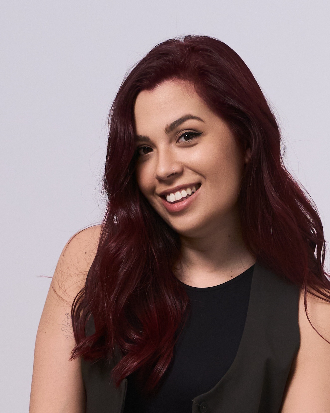 Woman with red hair and black top smiling, studio professional headshot