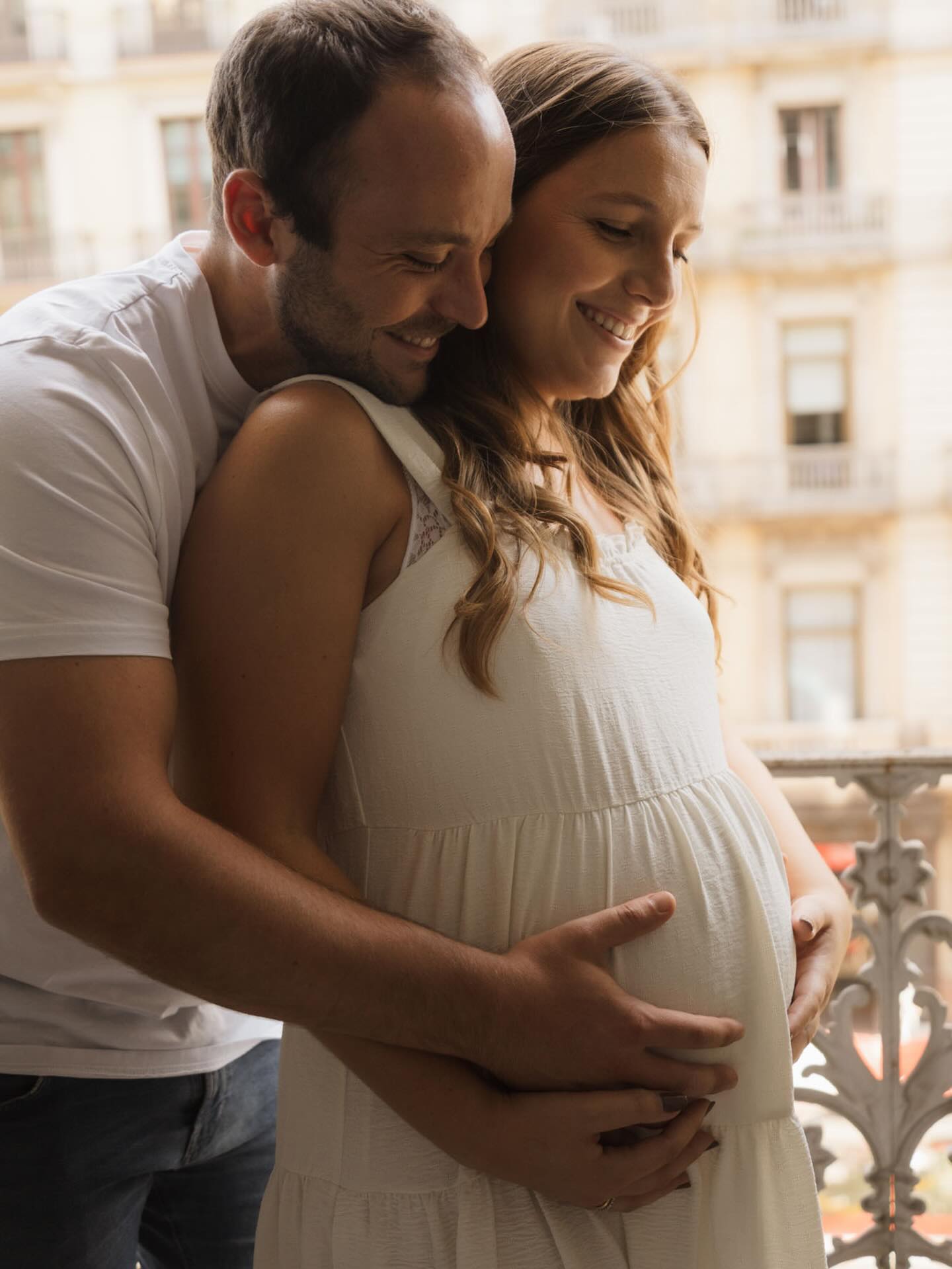 pareja en balcon fotos embarazada en casa abrazo vestido blanco ciudad
