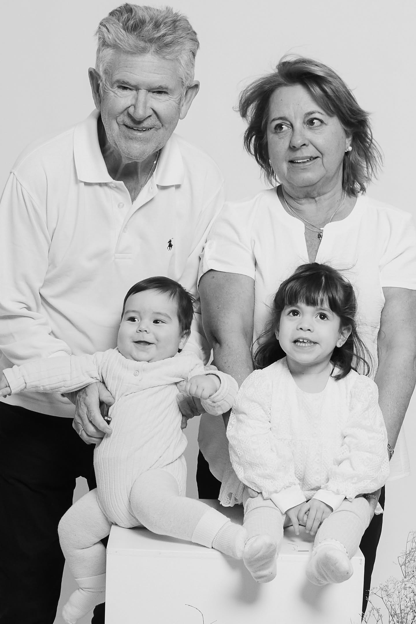 Grandparents posing in black and white with their two young grandkids, multigenerational family session at YOULO Barcelona