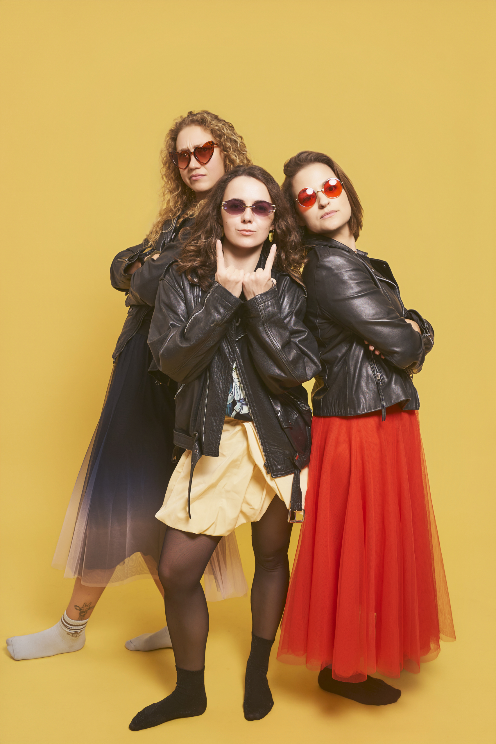 Tres amigas con cazadoras de cuero y faldas tul posando con confianza en sesión de despedida de soltera en estudio privado de Barcelona