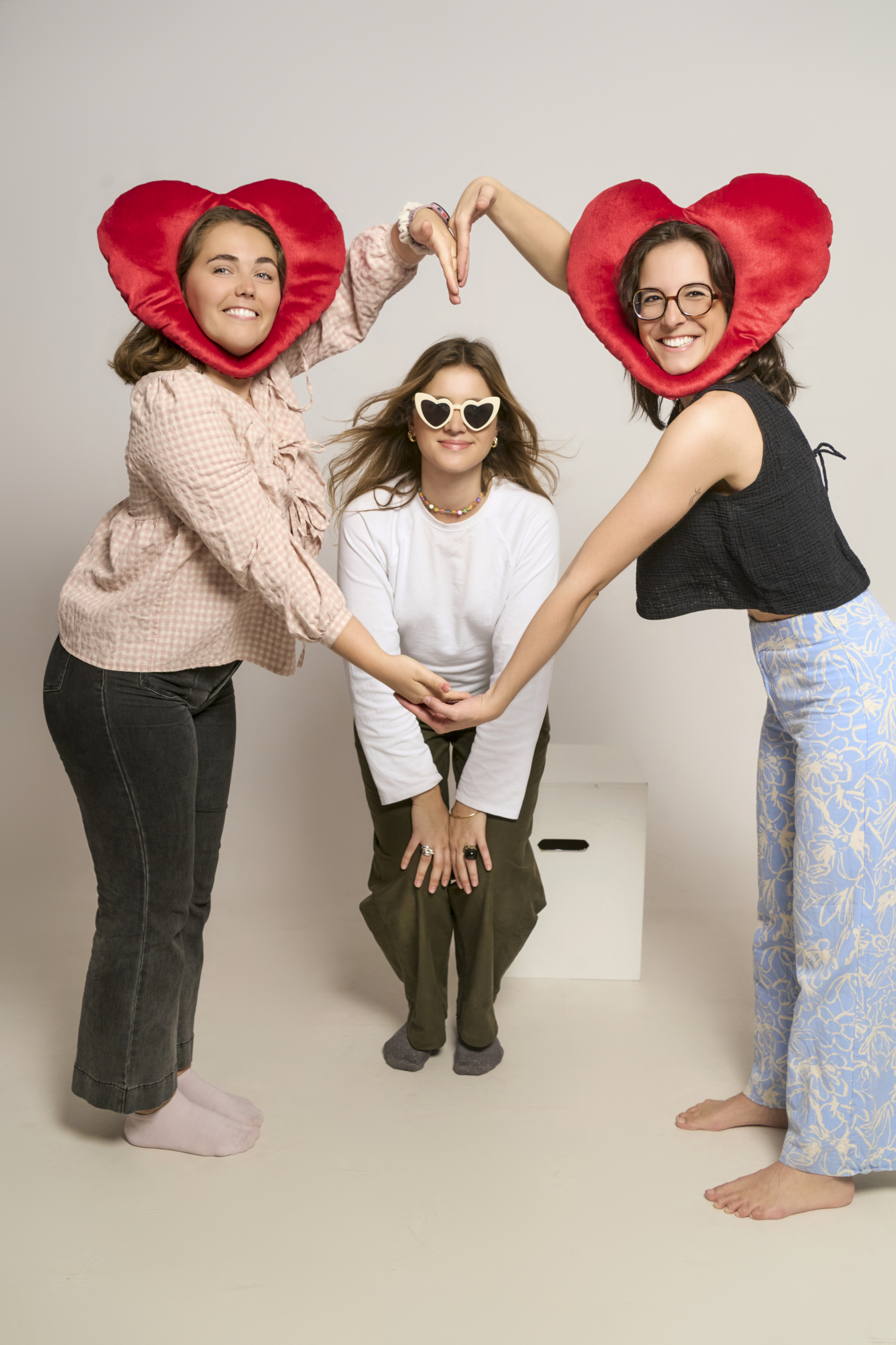 Tres amigas jugando con cojines de corazón en una sesión de fotos despedida de soltera Barcelona
