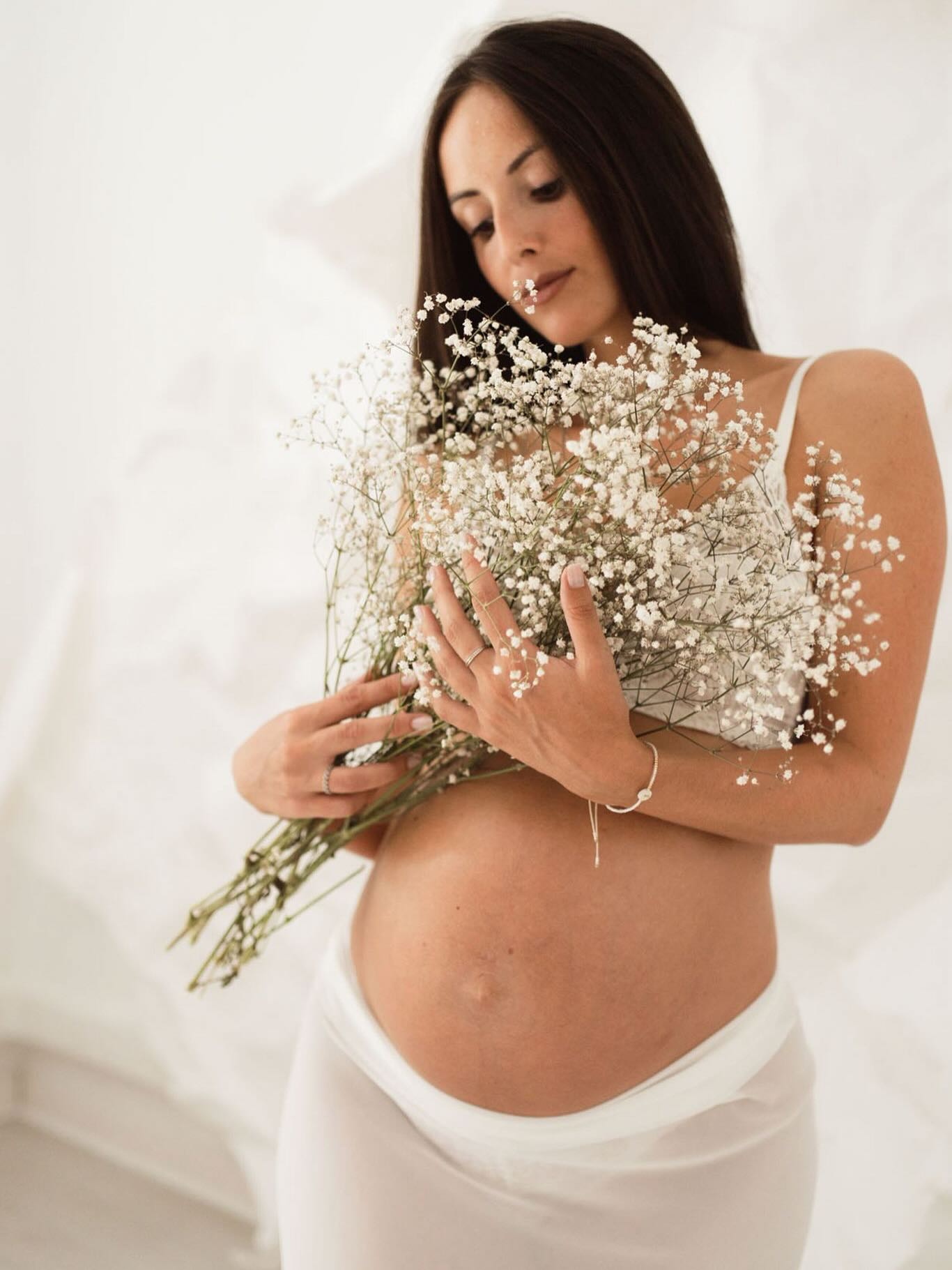 Sesión de fotos de embarazo durante babymoon en Barcelona — premamá con flores en estudio