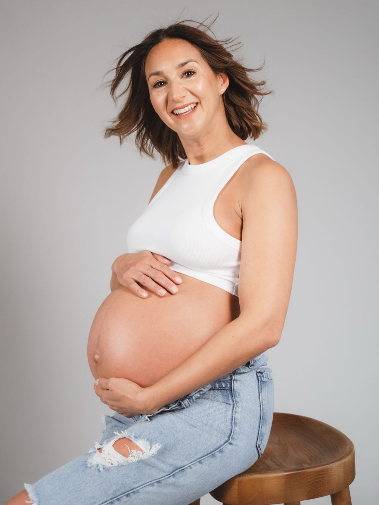 Mamá embarazada en la semana 30 con energía durante una sesión de fotos en estudio en Barcelona