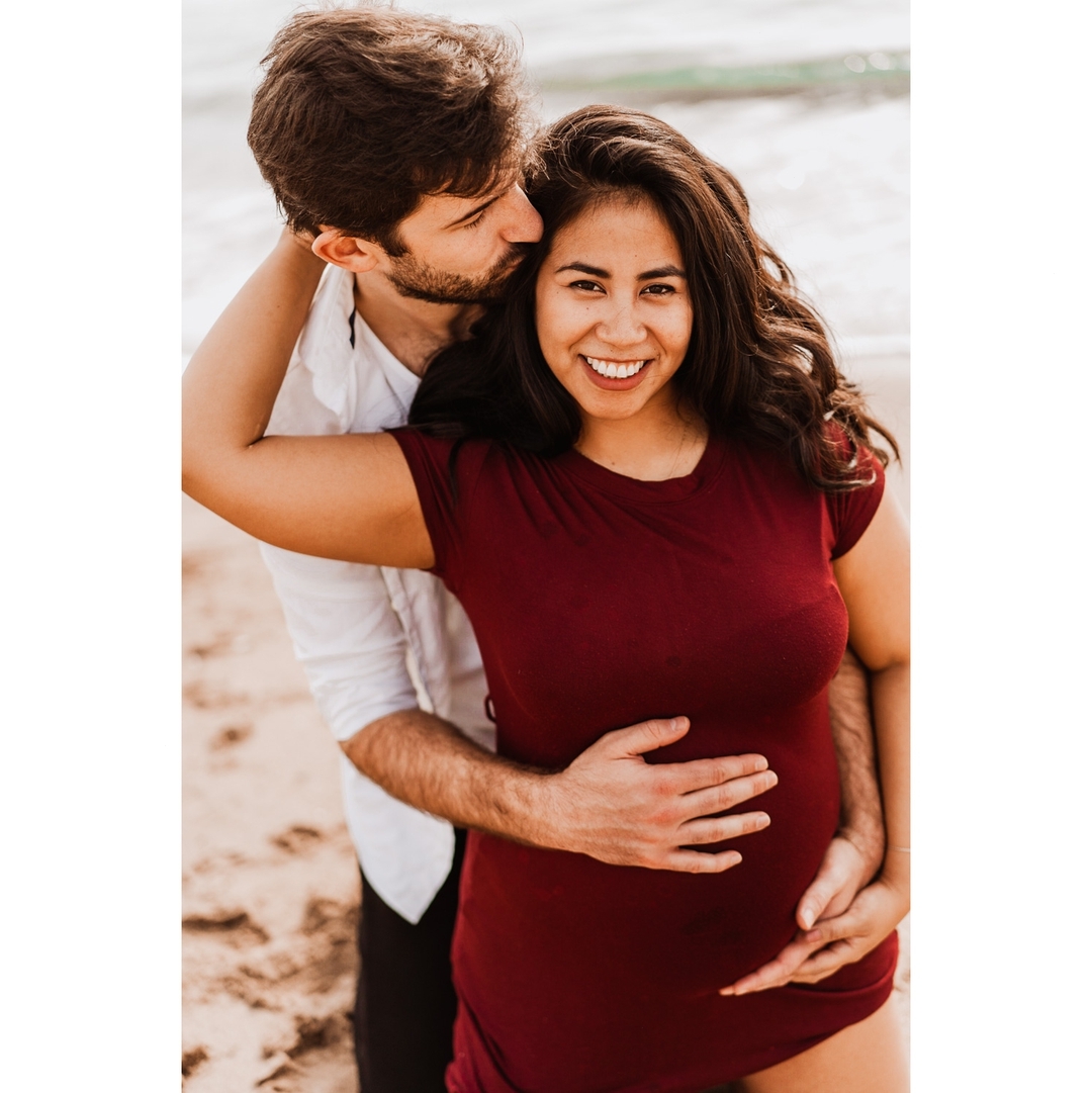 Pregnant couple on a Barcelona beach during a babymoon