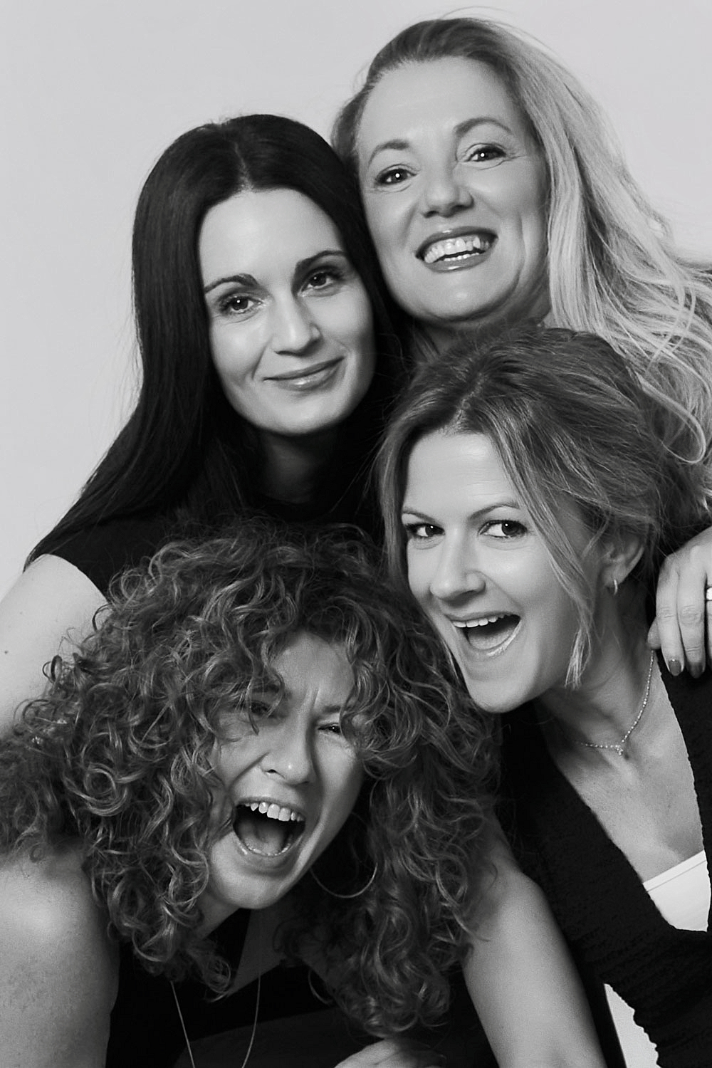 Four 40-year-old friends laughing together at YOULO Barcelona, black-and-white self-photo session