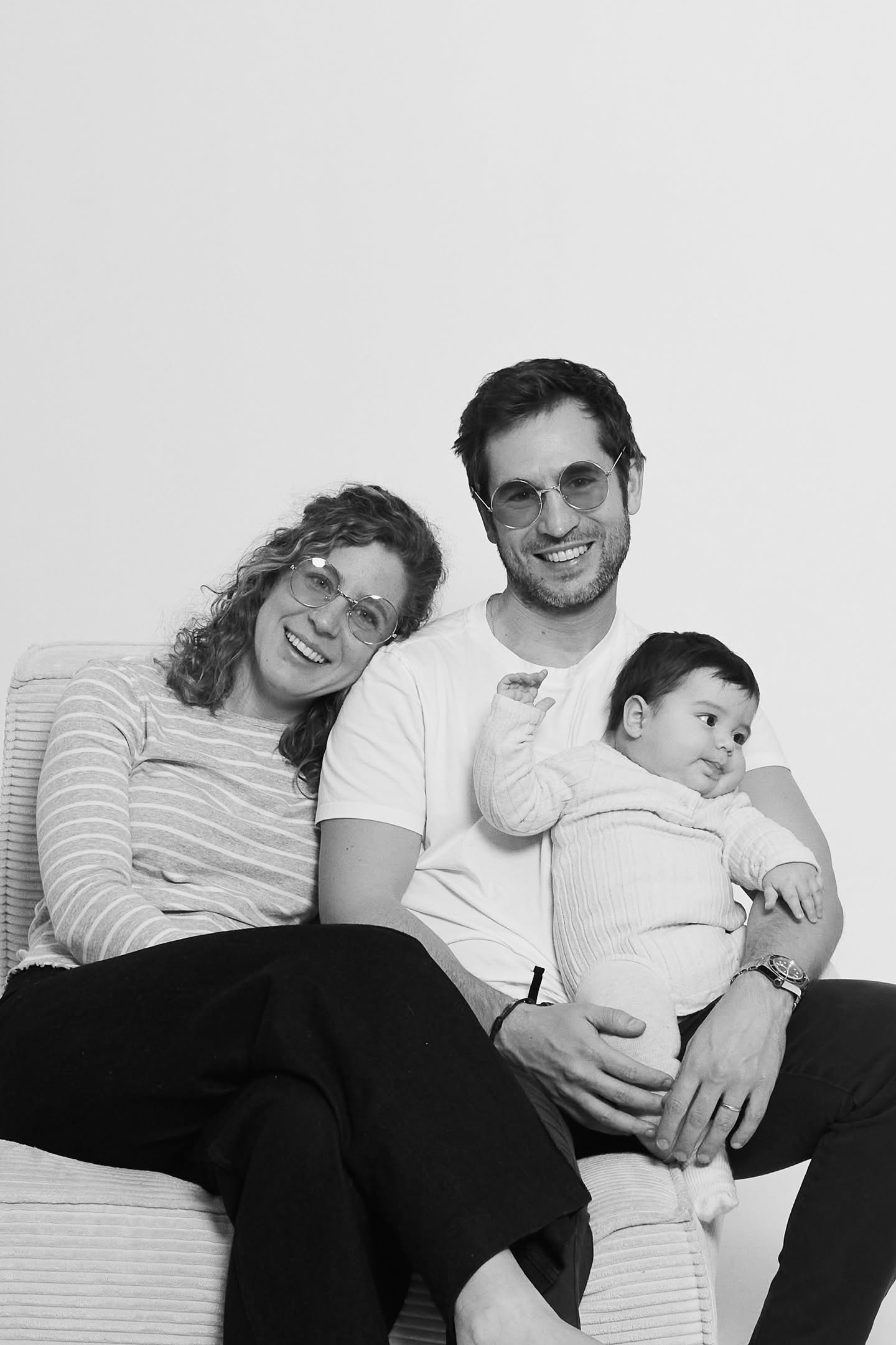 Family with baby on sofa dressed in neutral tones for photoshoot in Barcelona