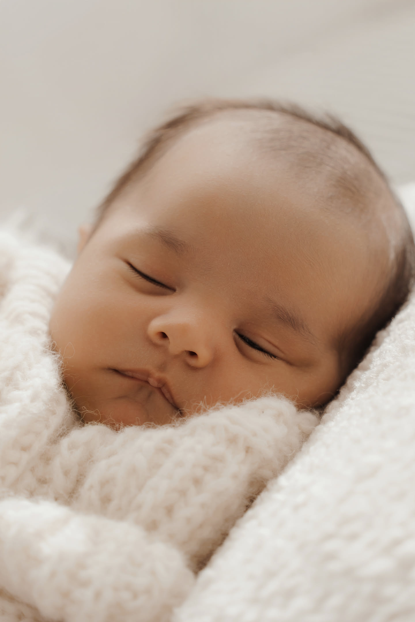 Newborn wrapped in a cotton blanket on a neutral backdrop in a Barcelona studio