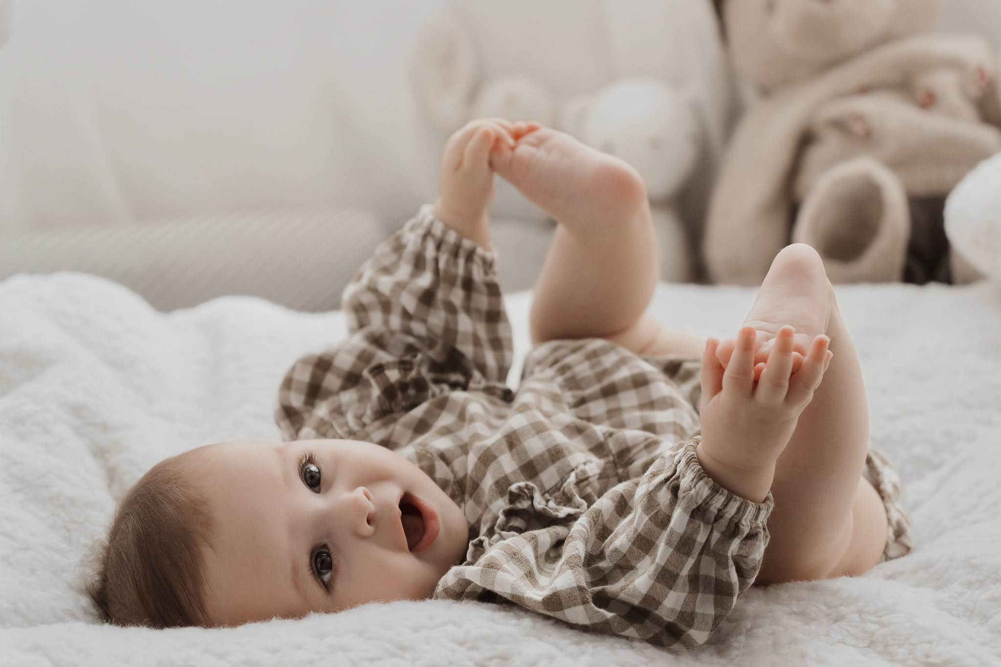 Bebé de 4 meses jugando con sus pies durante una sesión de fotos en el estudio de Eixample