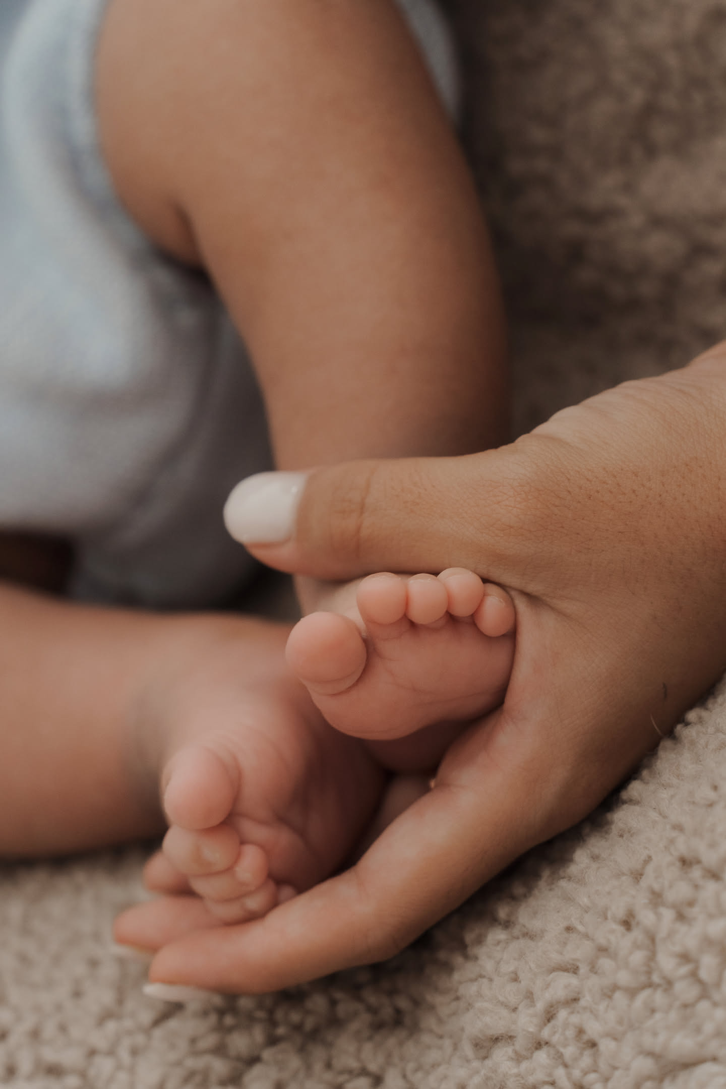 Baby feet held by mothers hands in a minimalist photoshoot detail
