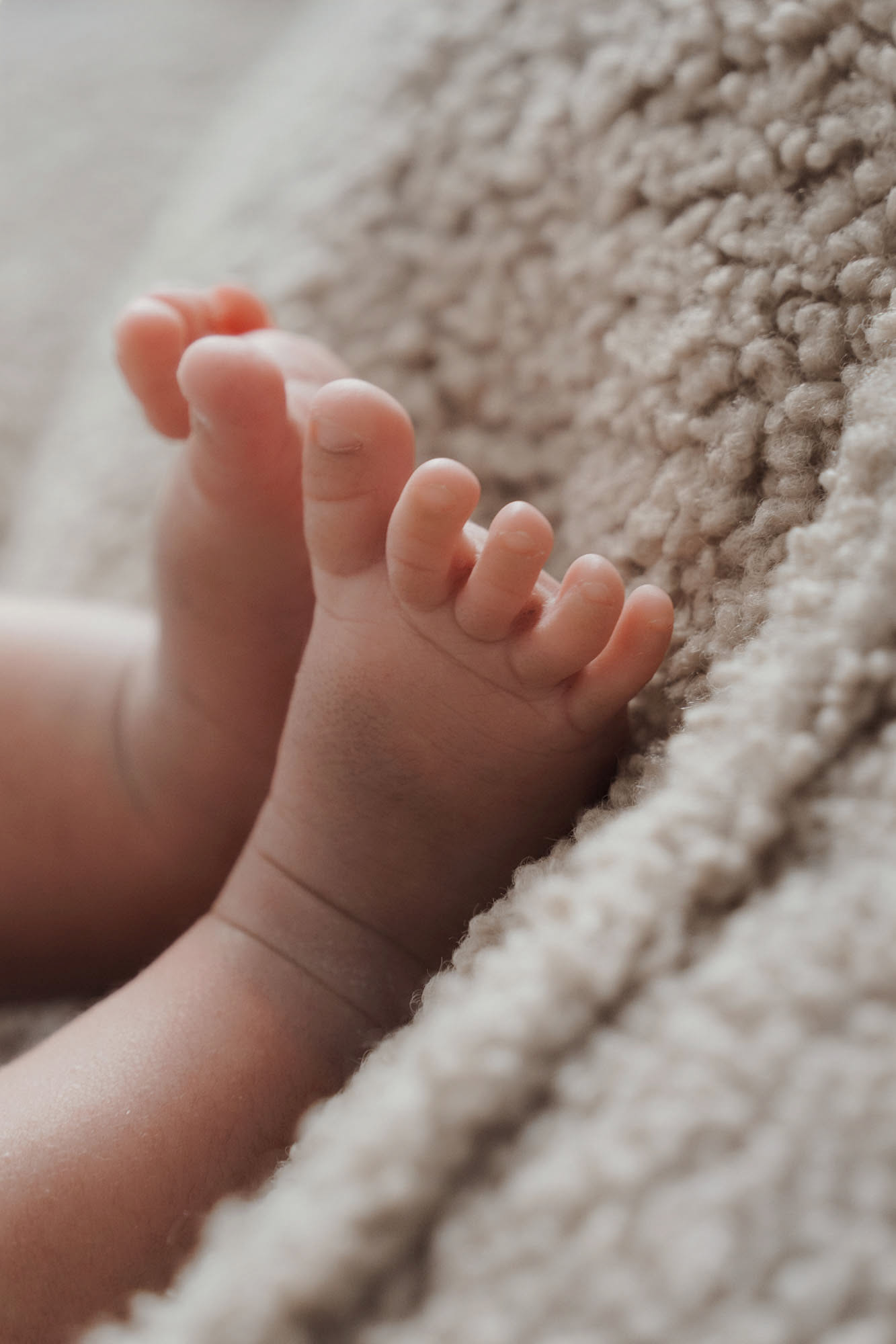 Bare baby feet on beige blanket in minimalist photoshoot