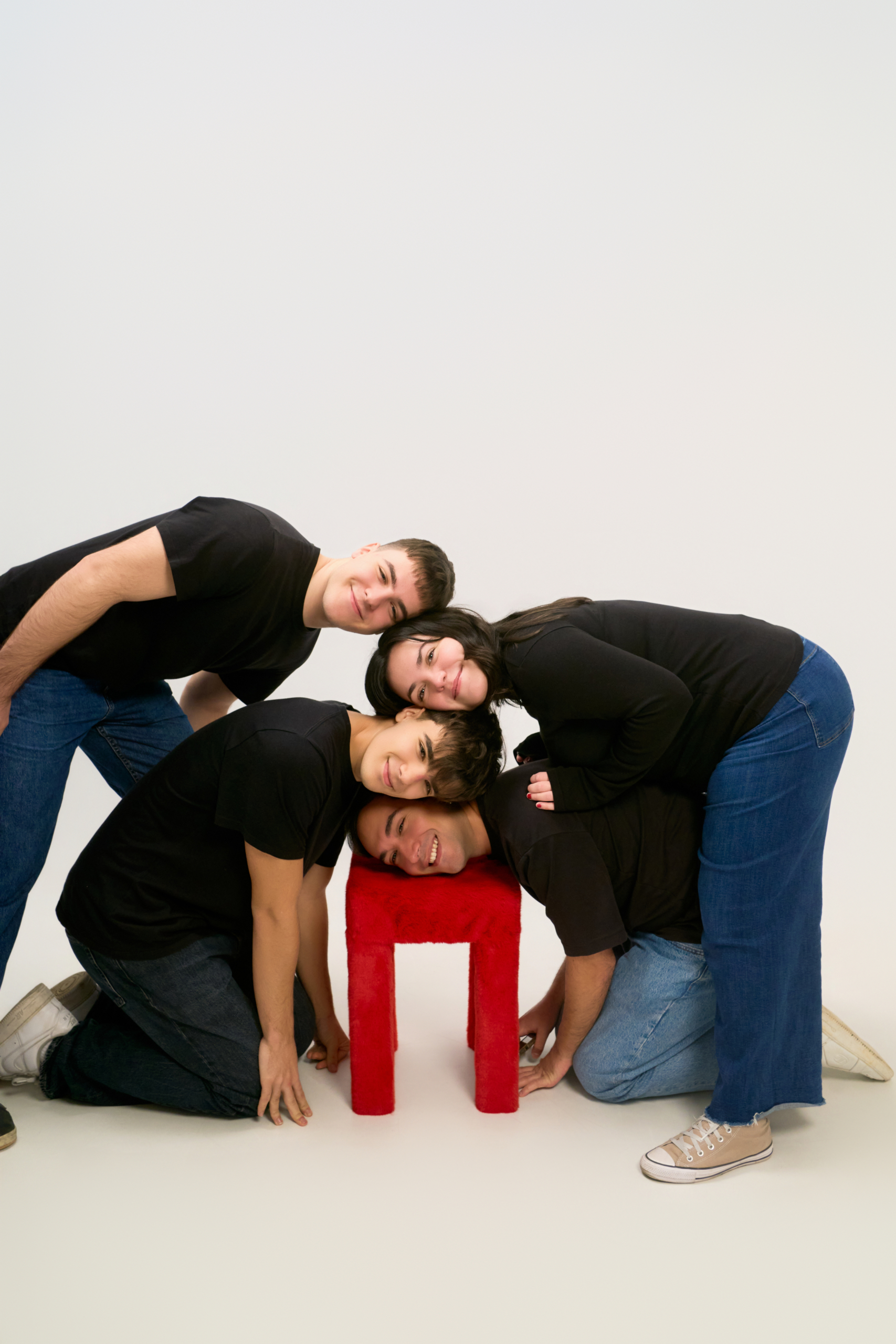 Grupo de amigos apoyando la cabeza en un taburete rojo en el estudio de autofoto
