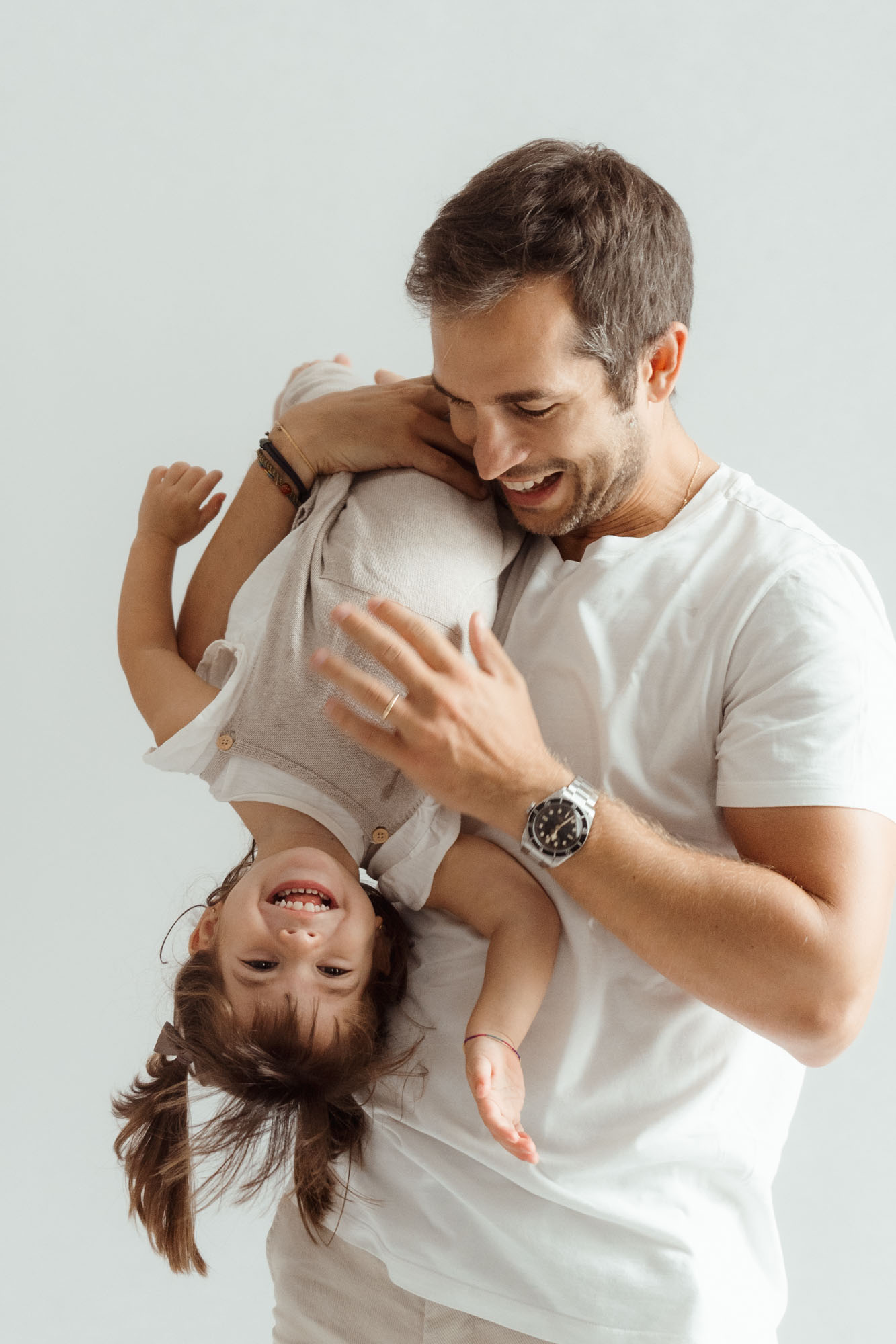 Padre sujetando en brazos a su hija boca abajo, los dos riendo a carcajadas