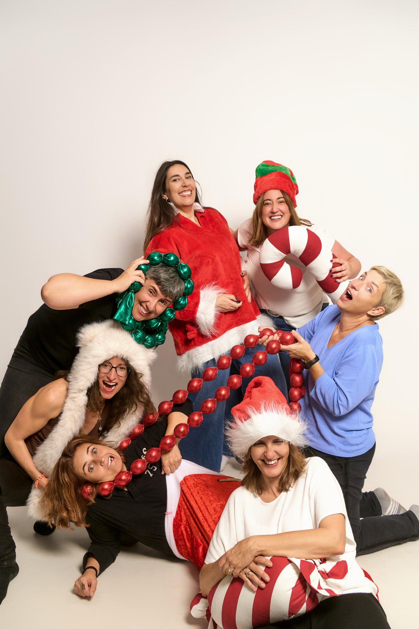 Grup d'amigues rient amb garlandes i gorros de Nadal a l'estudi YOULO